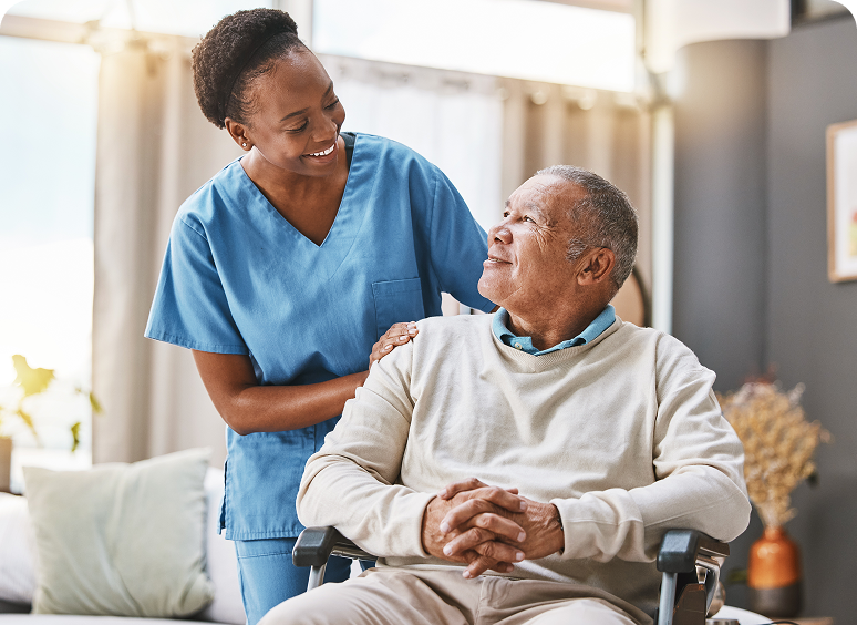 Caregiver smiling at elderly man in wheelchair.